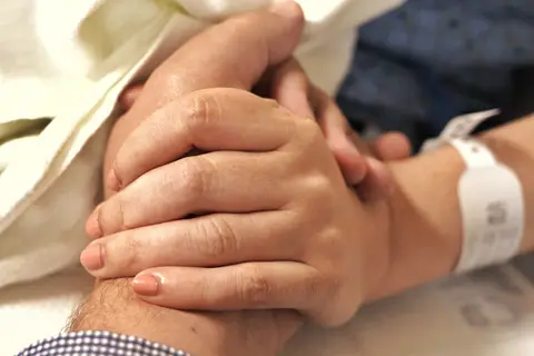 Dịch vụ nuôi bệnh TP.HCM — người nuôi bệnh nắm tay bệnh nhân đang nằm viện